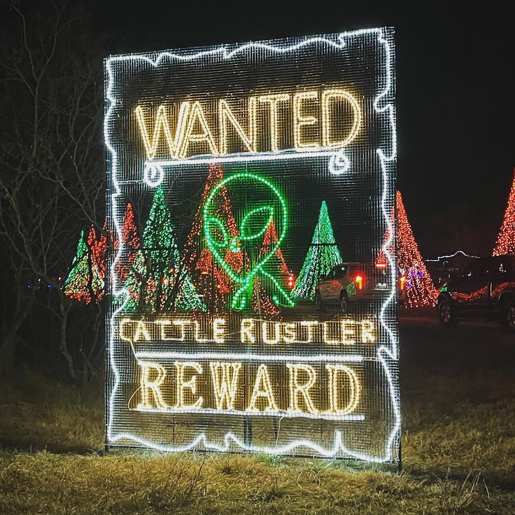 A neon sign that says wanted reward and cattle rustler.